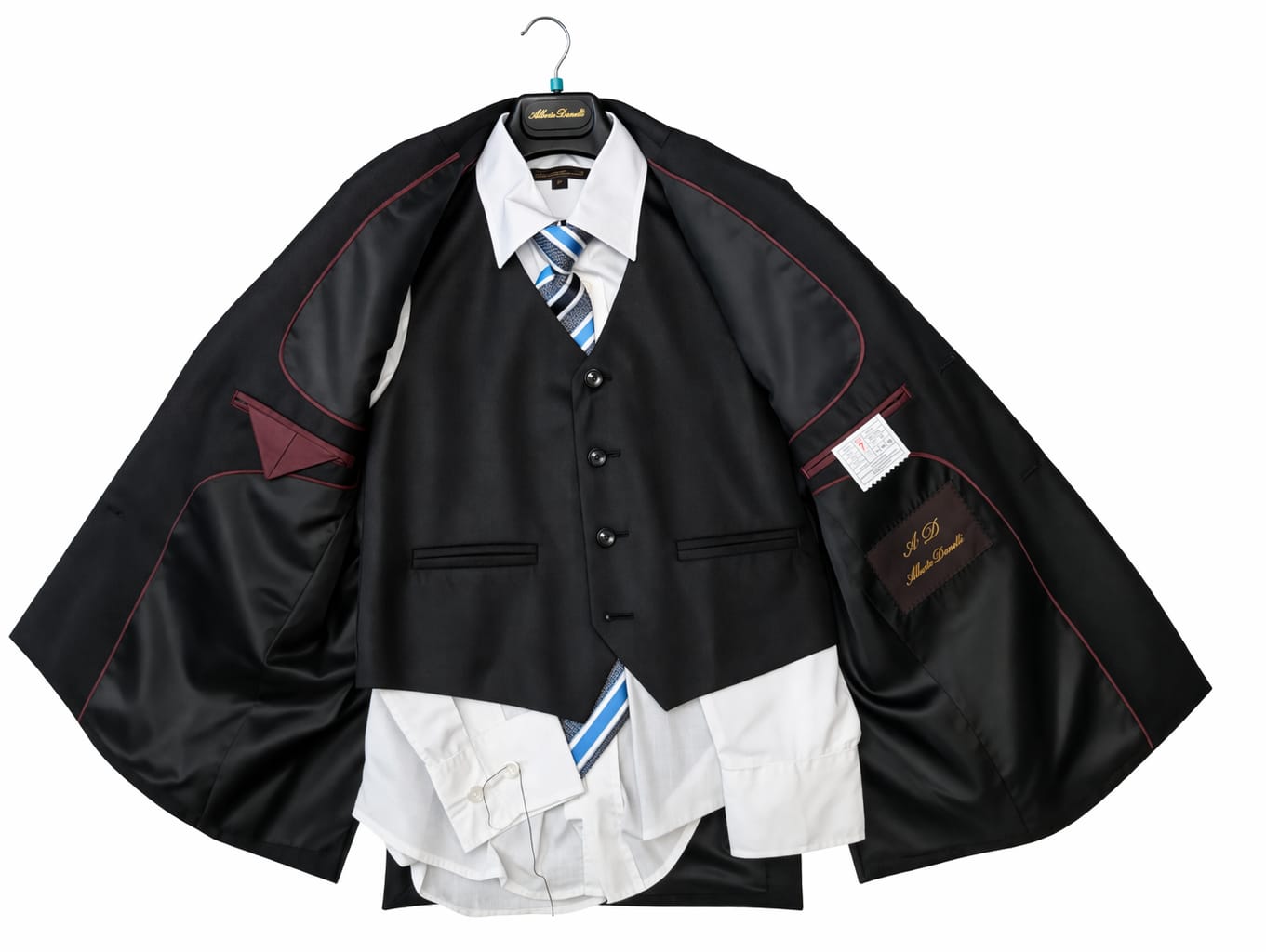 Black suit jacket with white shirt and blue tie on a hanger against a white background