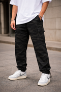 Person wearing black cargo pants and white sneakers on a street.