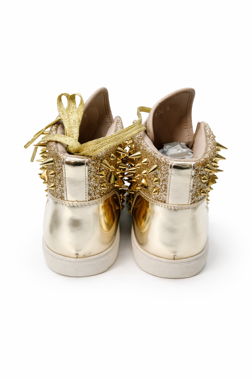 Gold and silver sneakers with spike details on a white background