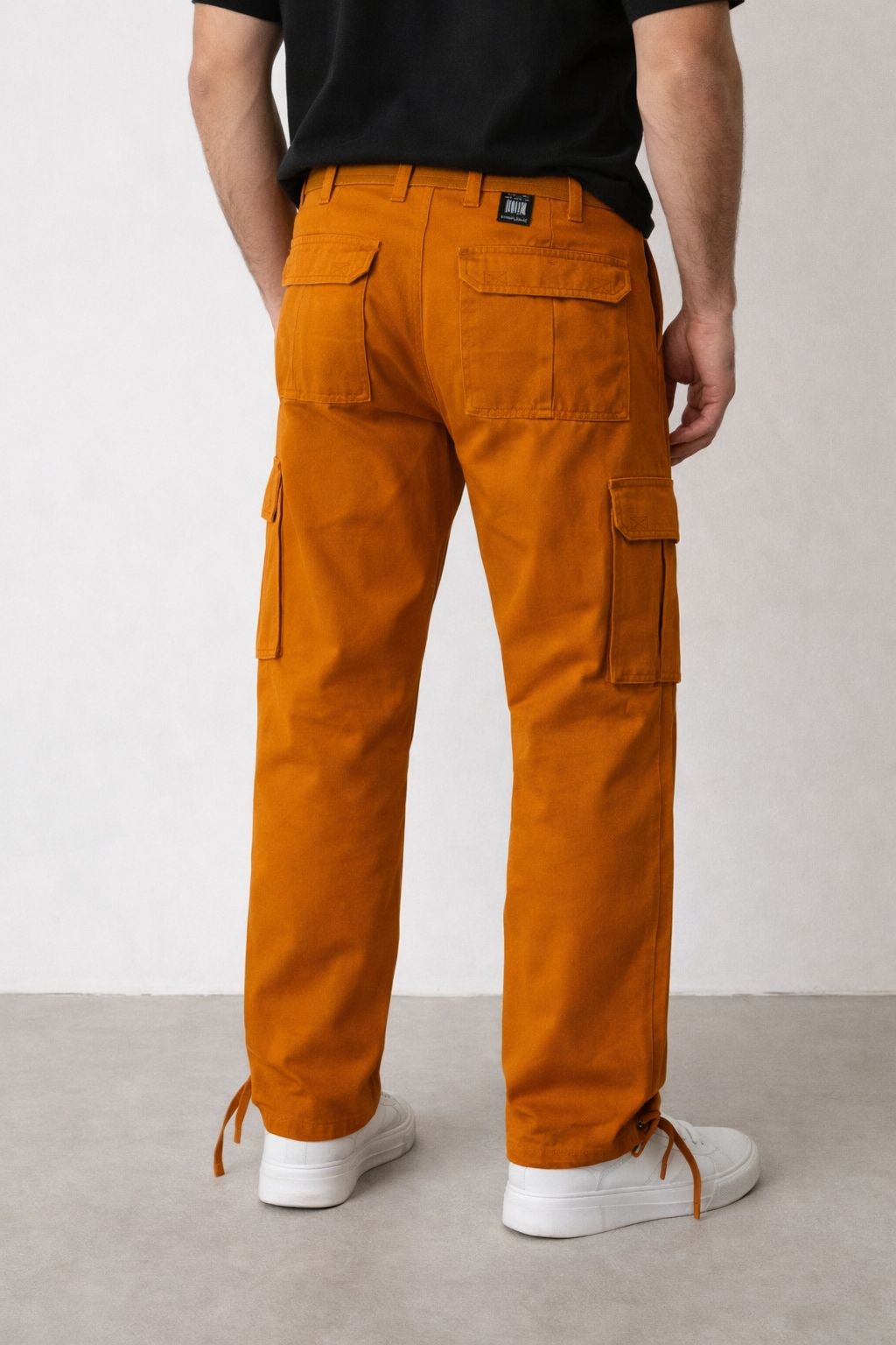 Person wearing orange cargo pants with a plain background