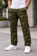 Person wearing green camouflage pants and white sneakers on a city street.