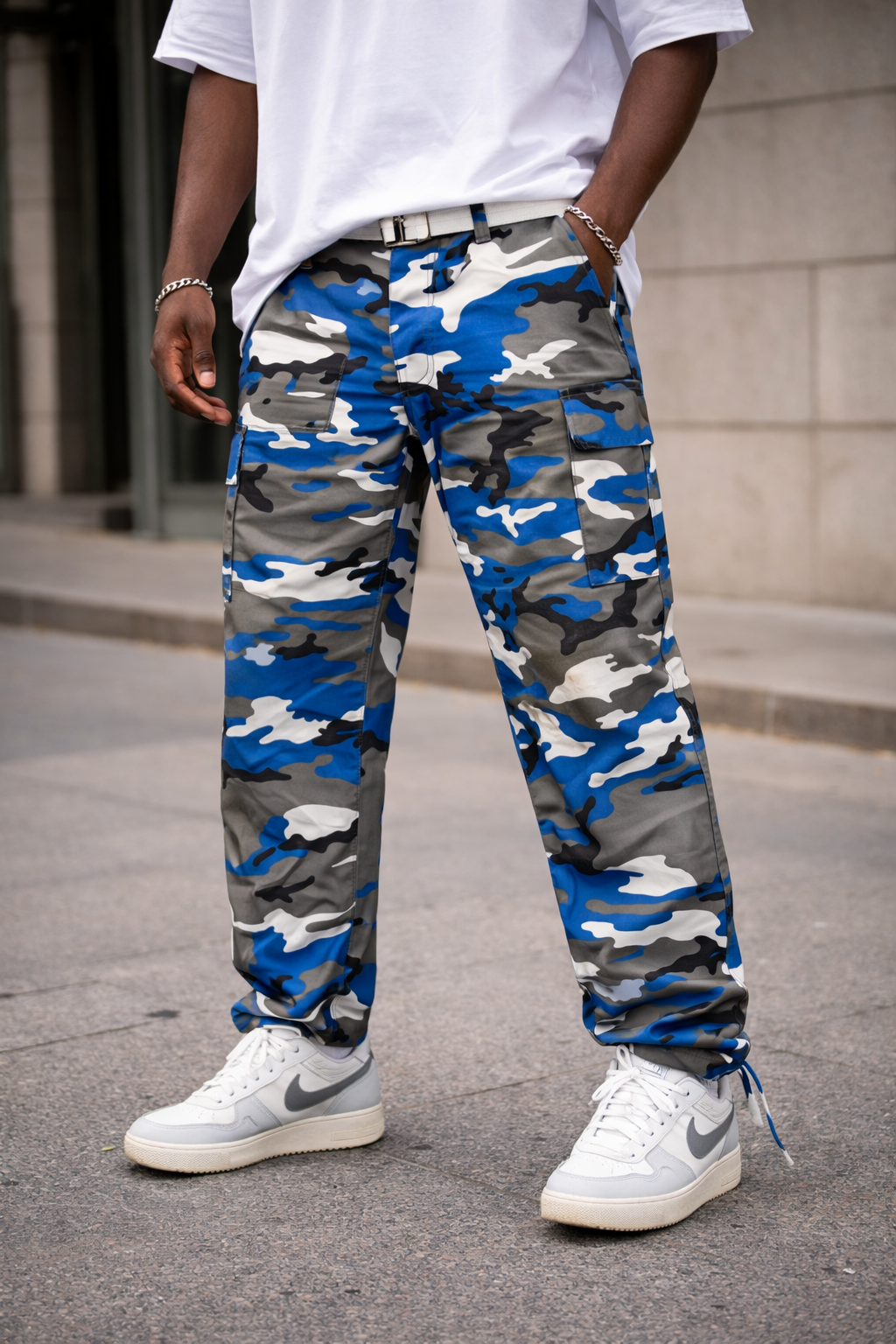 Person wearing blue and gray camouflage pants with white sneakers on a street.